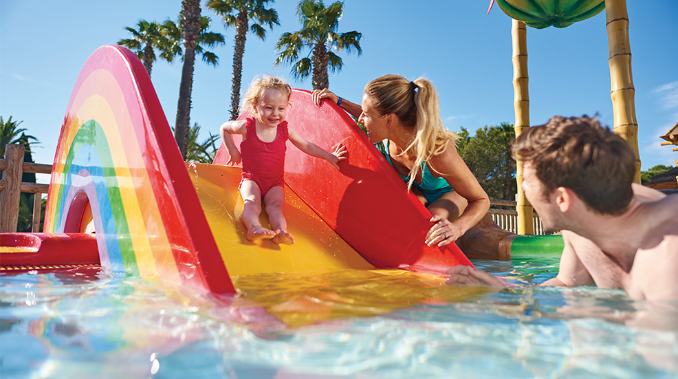 A couple and their young daughter enjoying the pool at Eurocamp